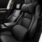 Black quilted neck pillow on the headrest and matching lumbar cushion on the seat of a car.