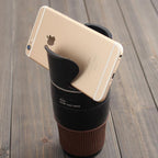 Smartphone slotted upright into the top grips of the black multi cup holder standing on a wooden table.