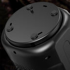 Close-up of the unit's dark matte base showing four round rubber non-slip feet and small vent holes.