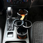 Overhead view of the black cup holder installed in a car console between the gear lever and centre armrest.