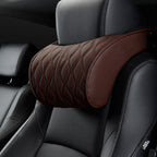 Close-up of the brown bone-shaped neck pillow strapped around the headrest, quilted face and strap visible.
