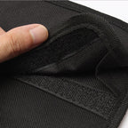 Close-up of the black woven fabric with a thumb lifting the hook-and-loop closure flap.