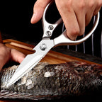In-use shot of hands cutting through a whole scaled fish on a wooden cutting board.