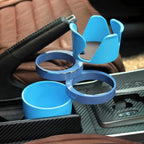 Blue multi cup holder fitted in a carbon-look car console beside the handbrake, both rings swung out.