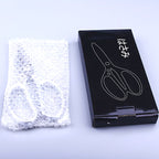 Packaging view: black box printed with a scissors outline and Japanese text, beside bubble wrap.