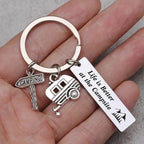 Held in a hand: the camping keychain with a CAMPING sign charm, a camper trailer charm and the engraved bar charm.