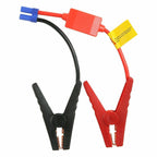 Red and black alligator jump clamps with copper teeth and a blue plug, on a white background
