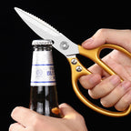 Gold-handled version of the shears prying open a bottle cap with the built-in opener notch.