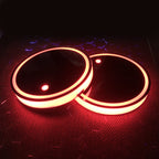 Two LED cup holder coasters glowing warm amber, glossy black tops and orange rims.