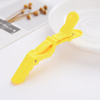 Yellow sectioning clip on a light flat-lay with dried flowers, a printed card and a white plate.