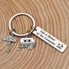 Keychain laid on a pale wood surface with concentric grain rings, showing the sign, trailer and quote charms.